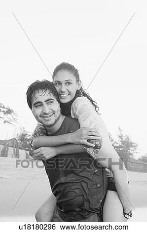 Stock Photograph - Young man smiling and piggybacking a young woman on his back. Fotosearch