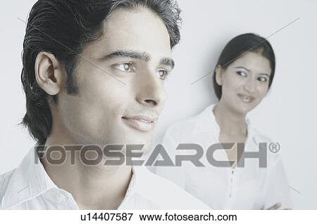 Stock Photo - Young man smiling with a young woman behind him. Fotosearch