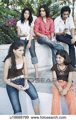 Stock Photo - Young woman and her sister looking at each other with three young people behind them. Fotosearch