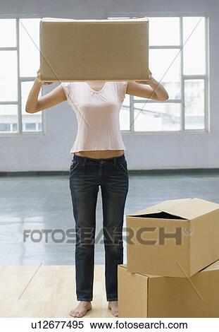 Stock Photography - Young woman holding a cardboard box in front of her face. Fotosearch