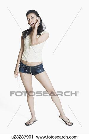 Stock Image - Young woman listening to an MP3 player and singing. Fotosearch