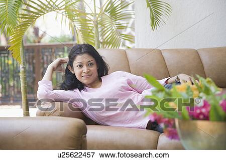 Young woman lying on a couch and smiling View Large Photo Image Stock Photo - Young woman lying on a couch and smiling. Fotosearch
