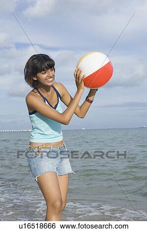 Young woman playing with a beach ball on the beach View Large Photo Image Stock Photograph - Young woman playing with a beach ball on the beach. Fotosearch