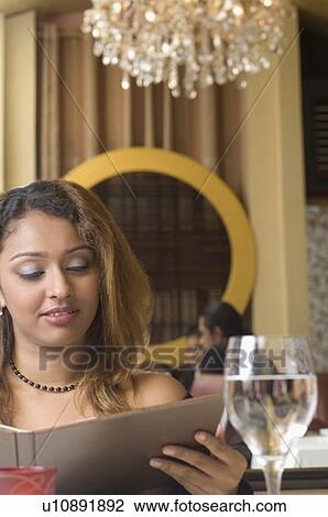 Young woman reading a menu in a restaurant View Large Photo Image Stock Image - Young woman reading a menu in a restaurant. Fotosearch