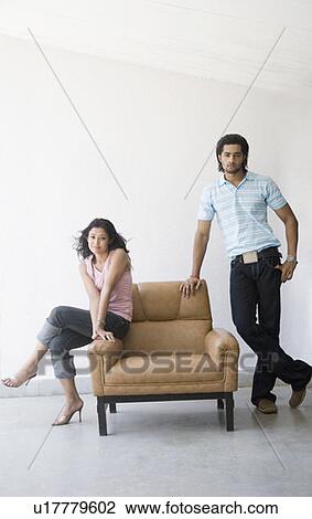 Young woman sitting in an armchair with a young man standing near her View Large Photo Image Stock Image - Young woman sitting in an armchair with a young man standing near her. Fotosearch
