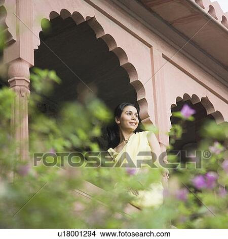 Picture - Young woman sitting on the railing of a palace, Neemrana Fort Palace, Neemrana, Alwar, Rajasthan, India. Fotosearch
