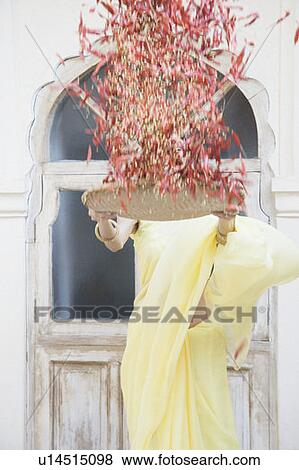 Stock Photo - Young woman spraying red chili peppers from a tray. Fotosearch