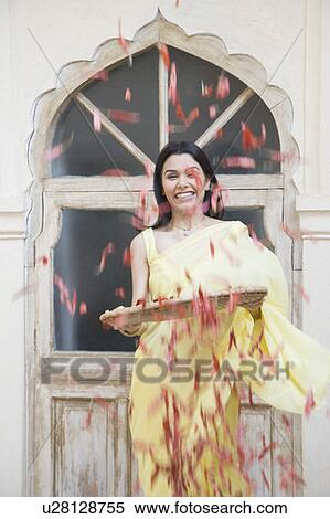 Stock Photography - Young woman spraying red chili peppers from a basket. Fotosearch