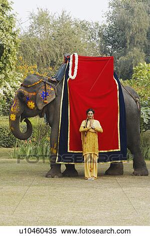 Stock Photography - Young woman standing in a prayer position beside an elephant. Fotosearch