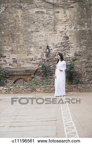 Young woman standing in front of a stone wall and smiling View Large Photo Image Stock Image - Young woman standing in front of a stone wall and smiling. Fotosearch