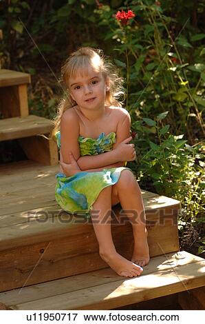 Stock Photo - 5 year old girl sitting on wooden steps. Fotosearch