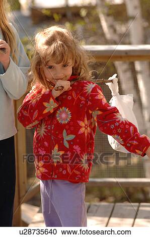 Stock Image - Girl in red jacket holding a stick. Fotosearch