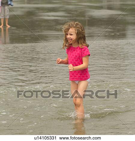 Stock Image - Girl standing in water on beach, Pacific Rim Park, Vancouver Island, Canada. Fotosearch