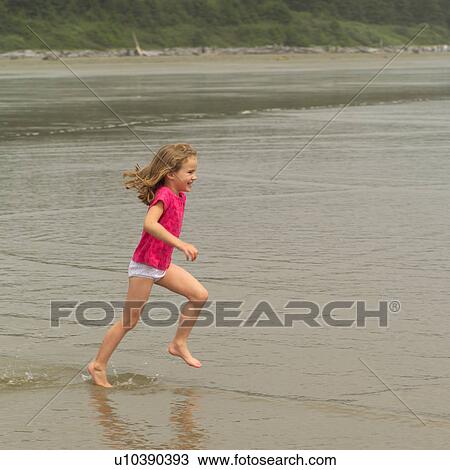 Stock Image - Young blond girl running on beach, Pacific Rim Park, Vancouver Island, Canada. Fotosearch