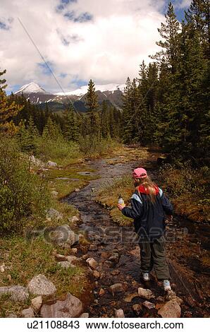Stock Image - Girl walking along stream of water, Jasper National Park, Canada. Fotosearch