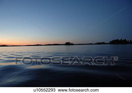 Stock Image - Silhouette of shoreline against twilight sky. Fotosearch