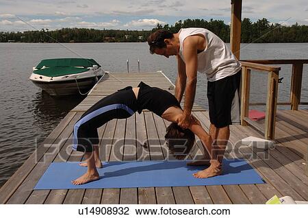 Couple doing yoga outdoors on a dock View Large Photo Image Stock Image - Couple doing yoga outdoors on a dock. Fotosearch