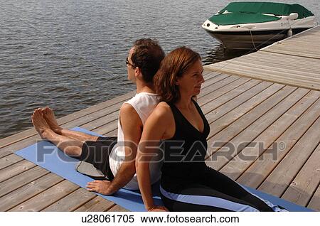 Stock Photography - Couple doing yoga outdoors on a dock. Fotosearch