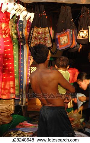 Stock Photo - Man holding a child in marketplace at Angkor Wat. Fotosearch