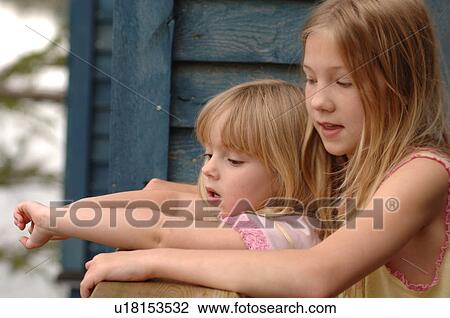 Stock Image - Two blond girls looking over handrail. Fotosearch