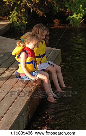 Two girls dangling their feet in the water View Large Photo Image Stock Photograph - Two girls dangling their feet in the water. Fotosearch