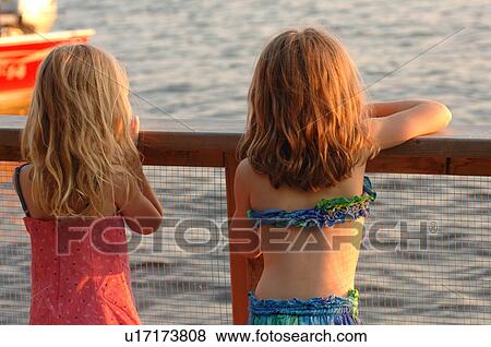 Stock Photo - Two girls looking over railing. Fotosearch