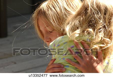 Stock Photo - Two young girls hugging each other. Fotosearch