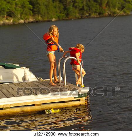 Two young girls standing on a pier in swimsuits View Large Photo Image Stock Image - Two young girls standing on a pier in swimsuits. Fotosearch