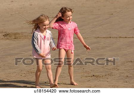 Two young girls standing on beach View Large Photo Image Stock Image - Two young girls standing on beach. Fotosearch