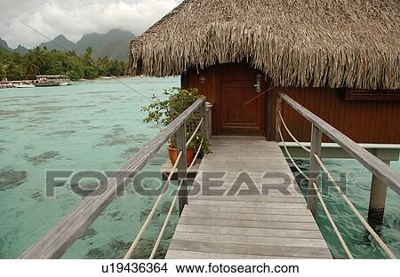 Picture - A pier with a thatched roof structure supported by stilts. Fotosearch