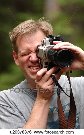 Stock Photograph - A young man using a camera. Fotosearch