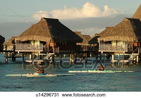 Stock Image - Thatched roof wooden structures built on stilts in the sea. Fotosearch