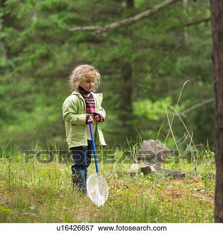 Stock Photo - Young girl holding a butterfly net in the woods. Fotosearch