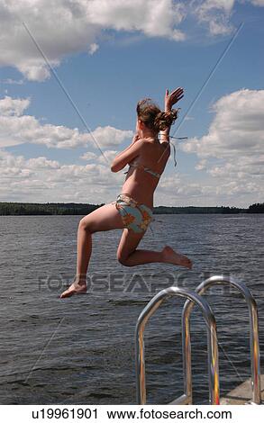 Stock Image - Young girl jumping into the Lake. Fotosearch