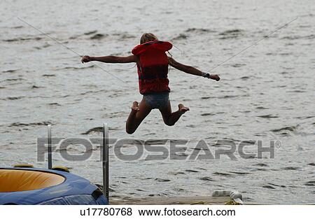 Stock Photo - Young girl wearing a lifejacket jumping of a raft. Fotosearch
