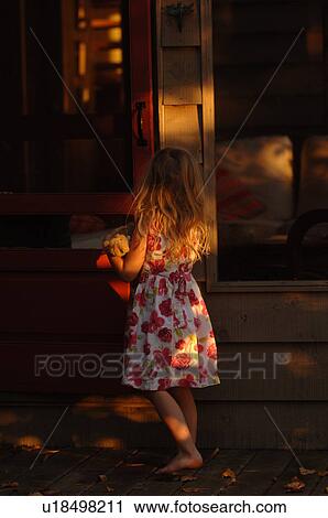 Stock Image - Back view of a 5 year old holding a doll. Fotosearch