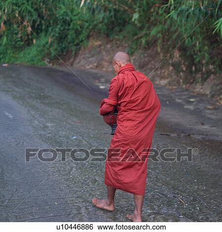 Stock Photograph - Monk walking barefoot up a road. Fotosearch