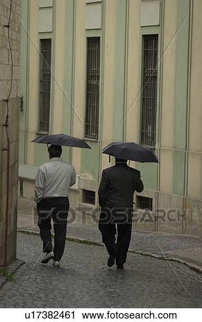 Rear view of people walking holding umbrella in Prague View Large Photo Image Stock Image - Rear view of people walking holding umbrella in Prague. Fotosearch