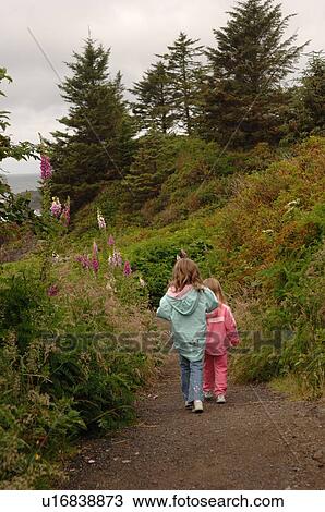 Stock Image - Two children walking along path in forest. Fotosearch