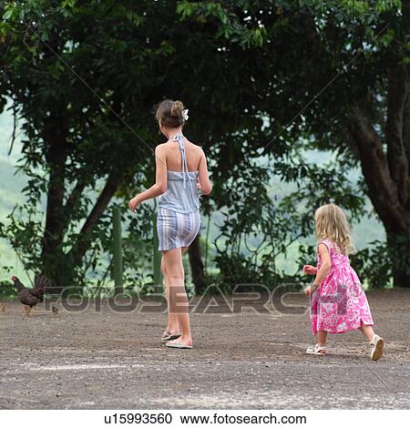 Stock Image - Two Girls Walking with Backs to Camera at Moorea in Tahiti. Fotosearch