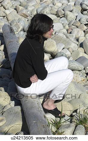 Stock Photography - Woman Sitting on Log. Fotosearch