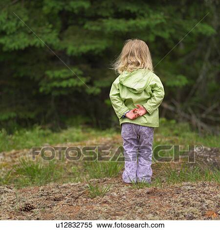 Stock Photography - Young girl standing in the woods. Fotosearch