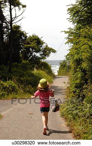 Stock Image - Young girl walking along path in forest. Fotosearch