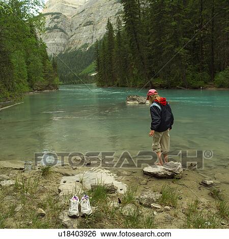 Stock Photograph - Young girl walking down hiking trail in forest. Fotosearch