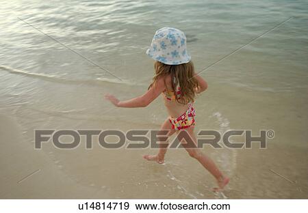 Young girl wearing a bikini running in water View Large Photo Image Stock Photo - Young girl wearing a bikini running in water. Fotosearch