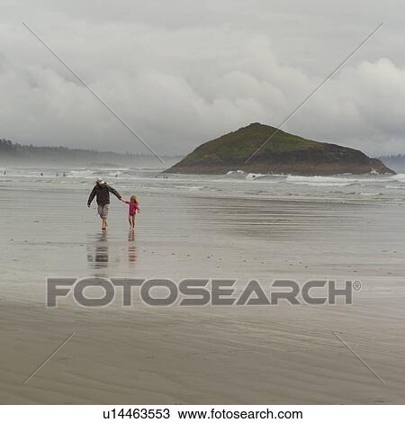 Stock Image - Adult walking with child on beach, Pacific Rim Park, Vancouver Island, Canada. Fotosearch