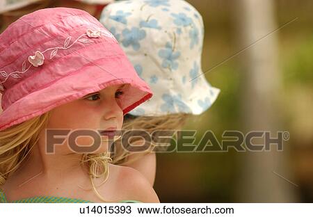 Stock Image - Close-up of a young girl wearing a pink sun hat. Fotosearch