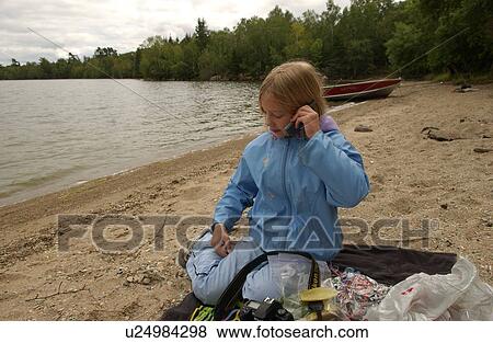 Stock Photo - Portrait of a young girl sitting on a beach talking on a mobile phone. Fotosearch