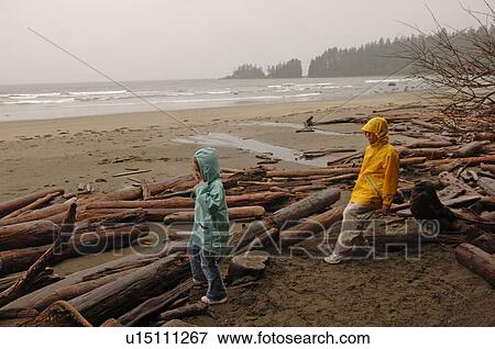 Stock Photo - Two children amongst logs on shoreline. Fotosearch