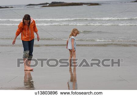 Two girls looking in the sand on ocean beach View Large Photo Image Stock Photograph - Two girls looking in the sand on ocean beach. Fotosearch